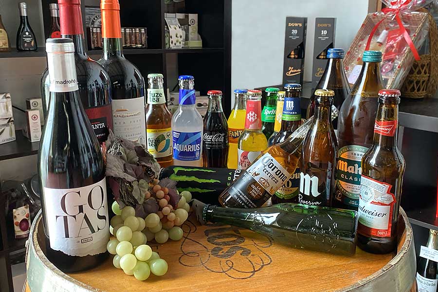 Botellas de vino, cerveza y refrescos de marcas reconocidas expuestas en un barril.