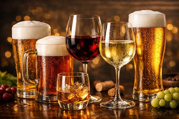 Variedad de bebidas alcohólicas como cerveza, vino y whisky sobre una mesa.