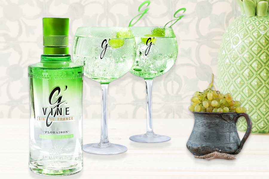 Botella de ginebra G'Vine Floraison junto a dos copas de cóctel con uvas.