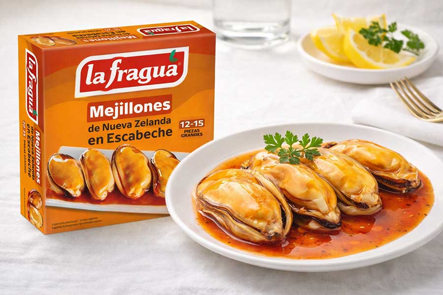 Caja de mejillones en escabeche marca La Fragua junto a un plato con cuatro mejillones.