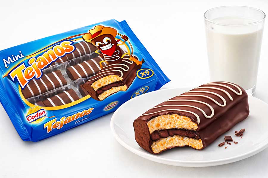 Pack de Mini Tejanos Codan y pastelito de chocolate, junto a un vaso de leche.